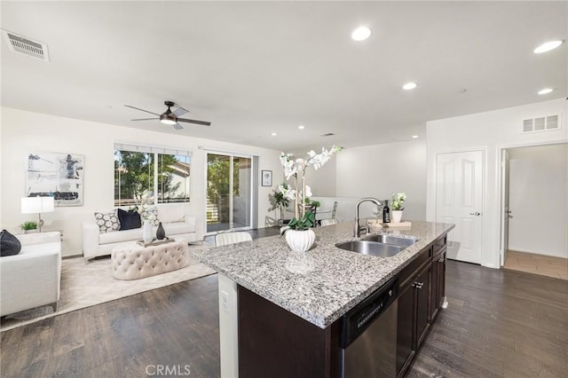 kitchen with sink, dark hardwood / wood-style flooring, stainless steel dishwasher, dark brown cabinetry, and a center island with sink