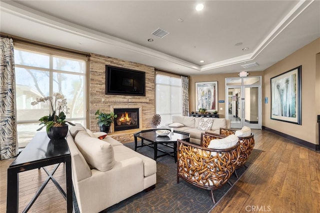 living room featuring hardwood / wood-style flooring, a fireplace, and a raised ceiling