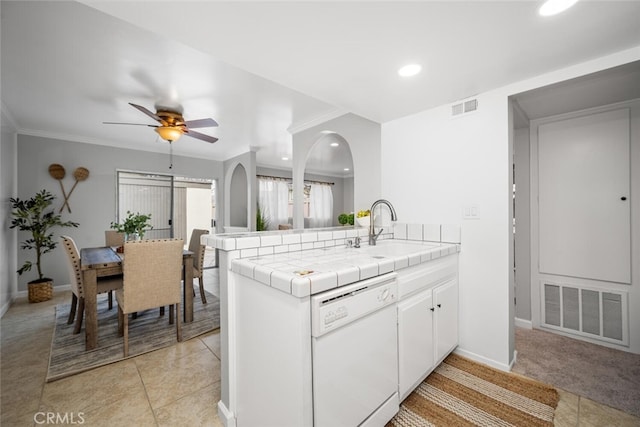 kitchen with sink, tile counters, white dishwasher, kitchen peninsula, and white cabinets