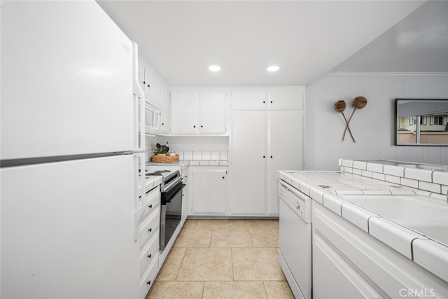 kitchen with light tile patterned flooring, white appliances, tile counters, and white cabinets