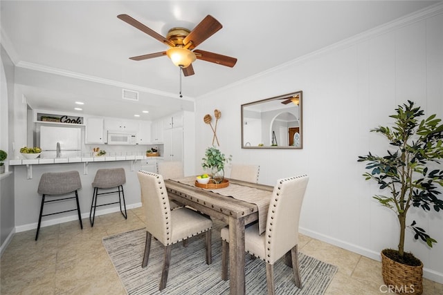 tiled dining area with ornamental molding and ceiling fan