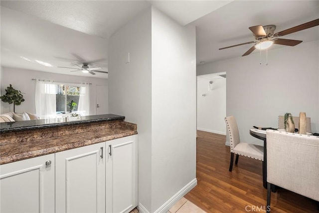 kitchen featuring hardwood / wood-style floors, white cabinetry, dark stone countertops, and ceiling fan