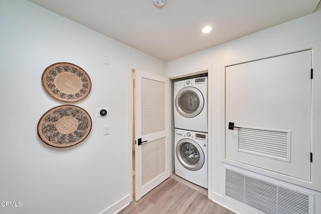 laundry room with stacked washer / drying machine and light hardwood / wood-style flooring