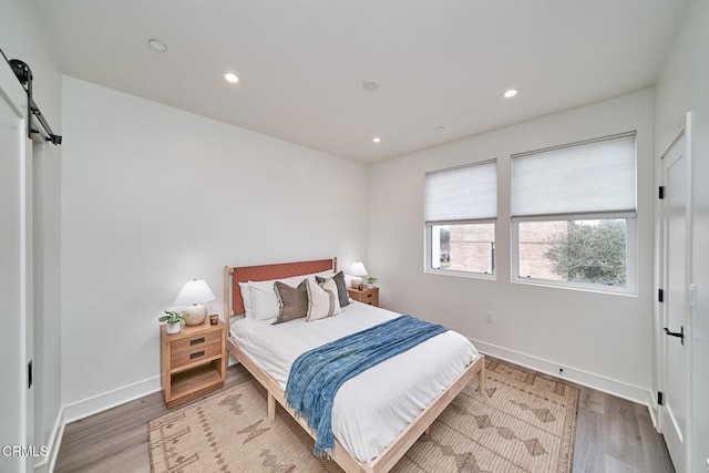 bedroom with a barn door and wood-type flooring