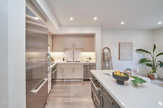 kitchen featuring sink, backsplash, light hardwood / wood-style floors, and stainless steel appliances