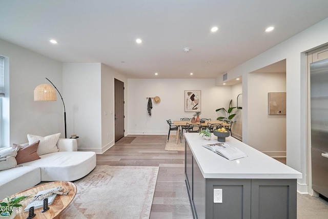 interior space with light wood-type flooring, a center island, stainless steel refrigerator, and gray cabinetry