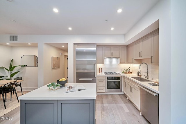 kitchen with gray cabinetry, sink, a kitchen island, light hardwood / wood-style flooring, and stainless steel appliances