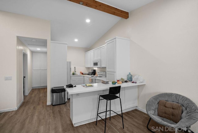 kitchen with kitchen peninsula, sink, white cabinets, white appliances, and a kitchen bar