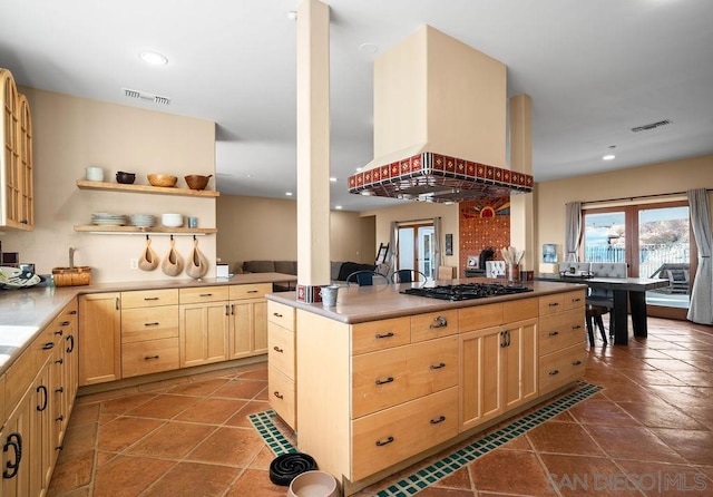 kitchen with light brown cabinetry, tile patterned flooring, island range hood, gas cooktop, and kitchen peninsula