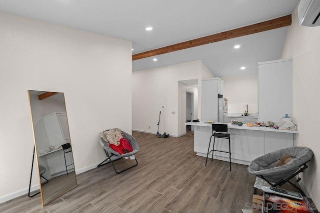 interior space with light wood-type flooring, a wall mounted AC, and beam ceiling