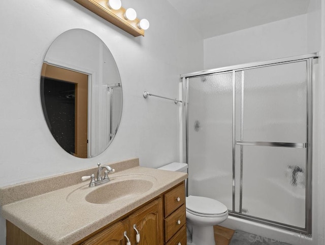 bathroom featuring vanity, a shower with shower door, and toilet