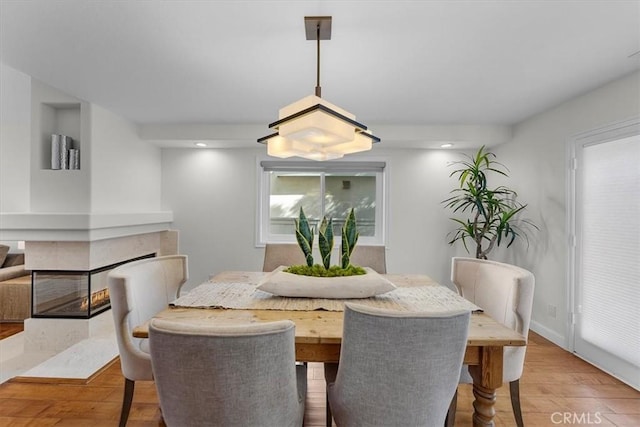 dining room with a multi sided fireplace and light hardwood / wood-style flooring