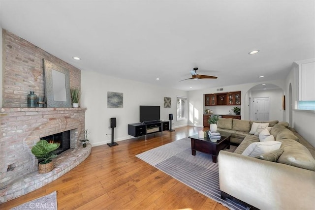 living room with ceiling fan, light hardwood / wood-style floors, and a fireplace