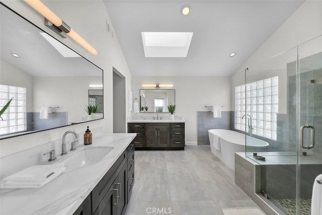 bathroom with independent shower and bath, lofted ceiling with skylight, and vanity