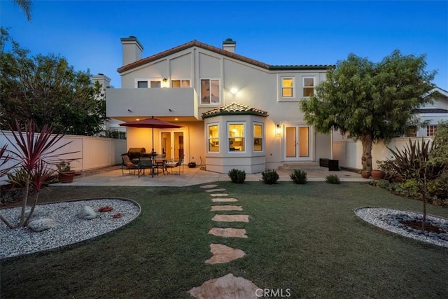 rear view of property with a lawn and a patio