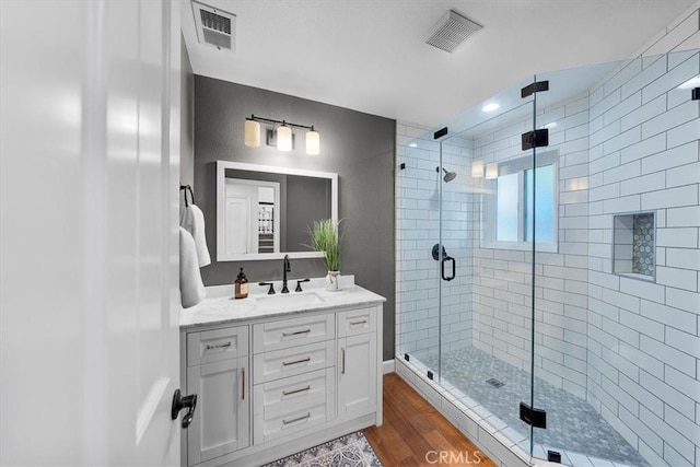 bathroom featuring vanity, a shower with door, and wood-type flooring