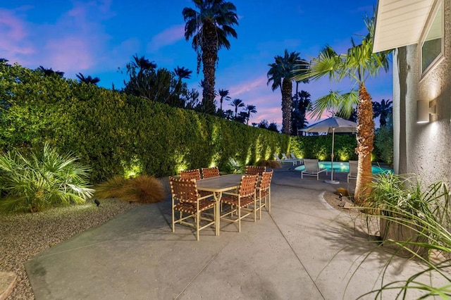 patio terrace at dusk featuring a swimming pool