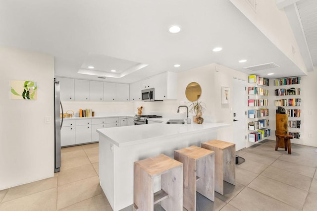 kitchen featuring kitchen peninsula, white cabinets, sink, and appliances with stainless steel finishes