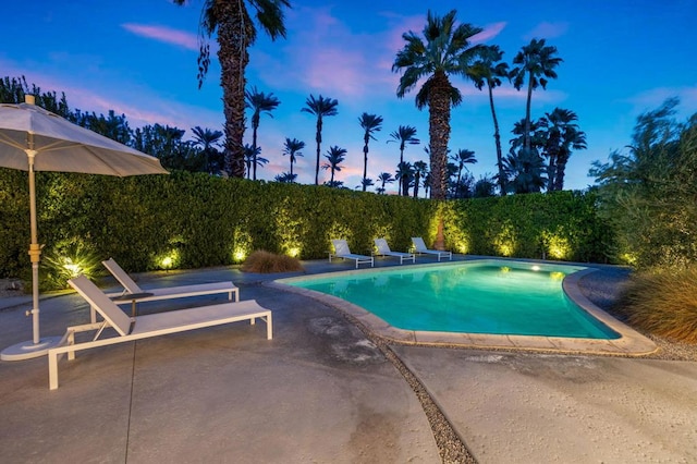 pool at dusk with a patio area