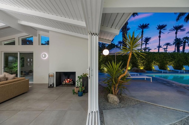 patio terrace at dusk featuring a fenced in pool and exterior fireplace