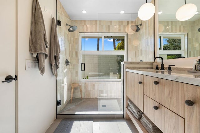 bathroom with a shower with door, plenty of natural light, tile patterned floors, and vanity