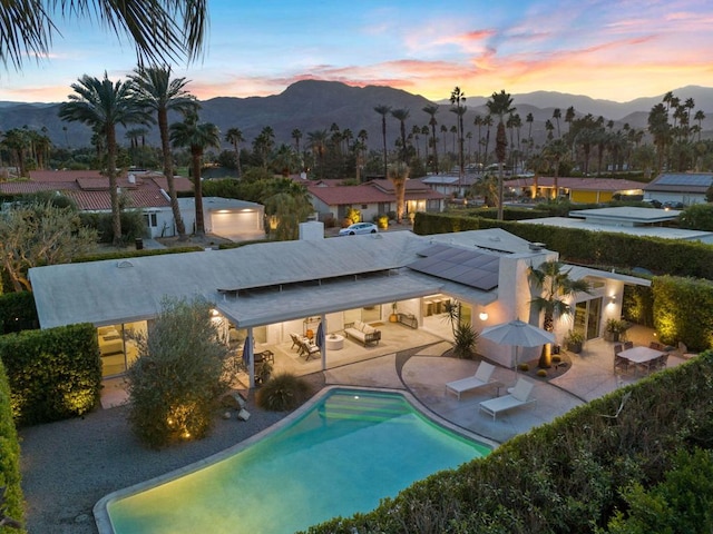 pool at dusk featuring a mountain view and a patio area