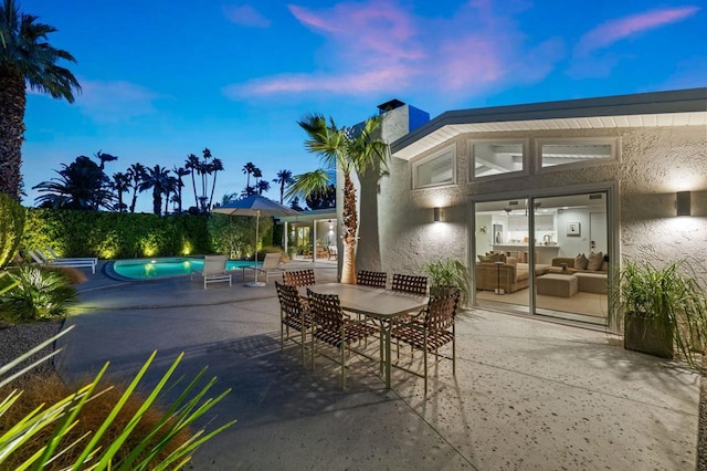 patio terrace at dusk featuring a fenced in pool and an outdoor living space