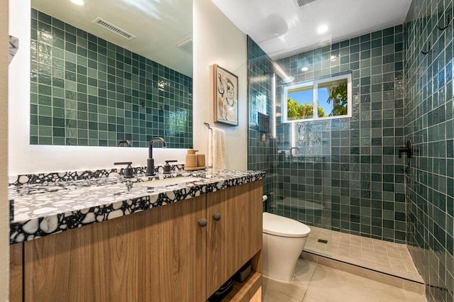 bathroom with vanity, toilet, tiled shower, and tile patterned flooring