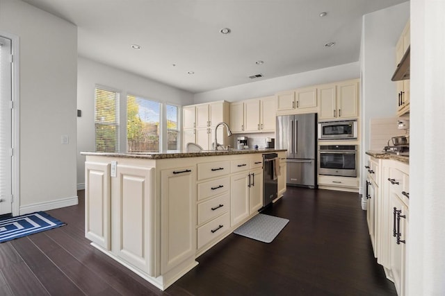 kitchen featuring cream cabinetry, tasteful backsplash, a kitchen island with sink, and stainless steel appliances