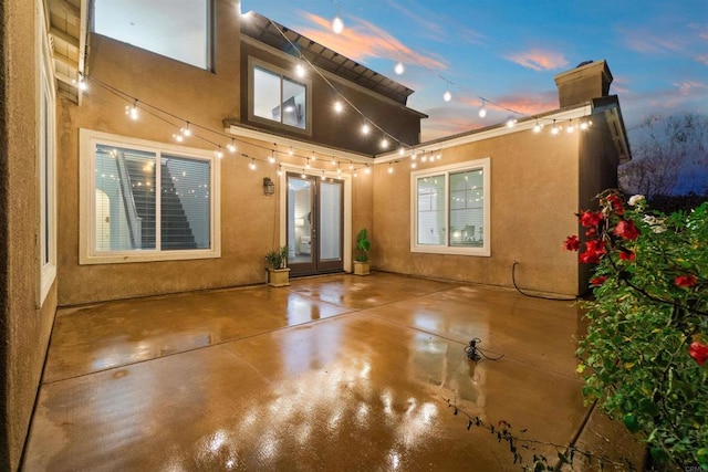 back house at dusk featuring a patio