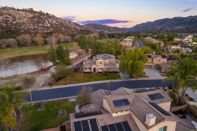 aerial view at dusk featuring a water and mountain view