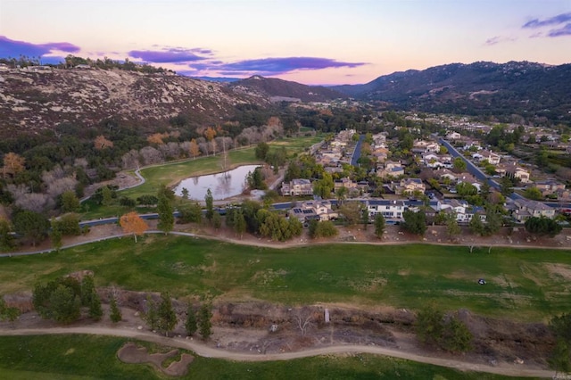 aerial view at dusk featuring a water and mountain view