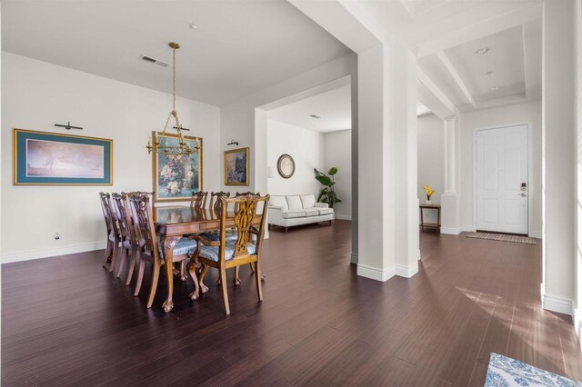 dining space featuring ornate columns, an inviting chandelier, and dark hardwood / wood-style floors