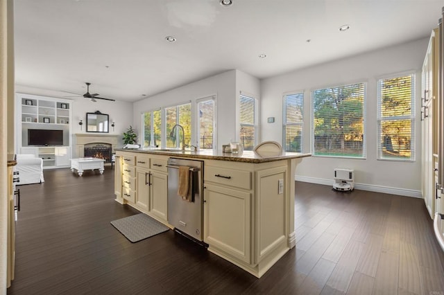 kitchen with stainless steel dishwasher, sink, an island with sink, light stone counters, and plenty of natural light