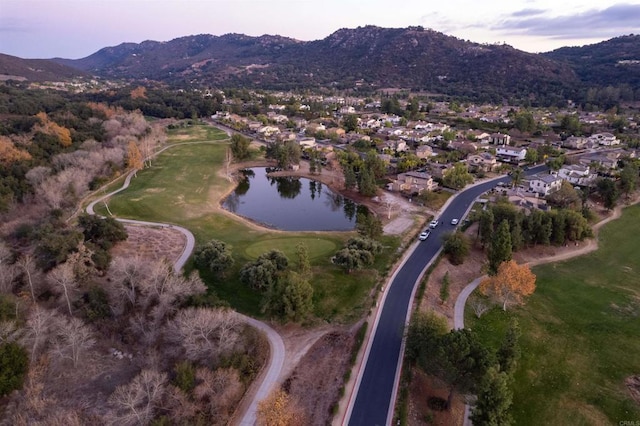 aerial view at dusk featuring a water and mountain view