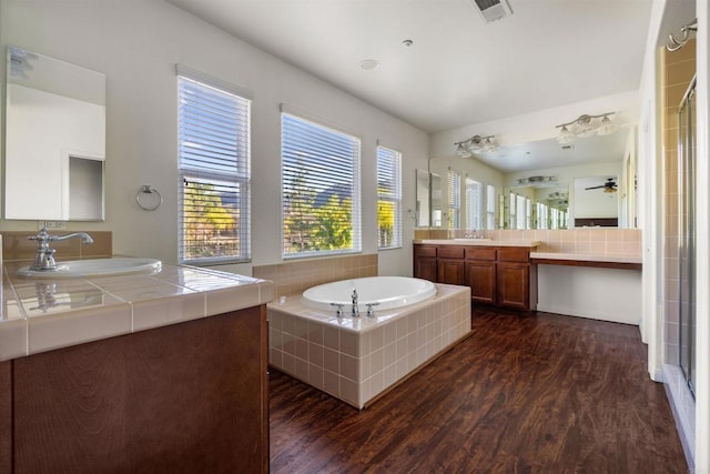 bathroom featuring vanity, ceiling fan, tiled tub, and wood-type flooring