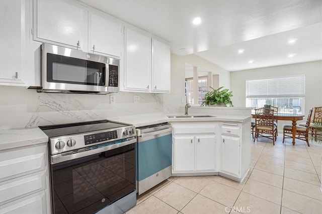 kitchen with appliances with stainless steel finishes, sink, white cabinets, backsplash, and light tile patterned floors