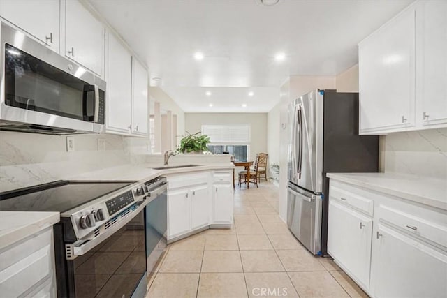 kitchen featuring white cabinetry, sink, light tile patterned floors, stainless steel appliances, and light stone countertops