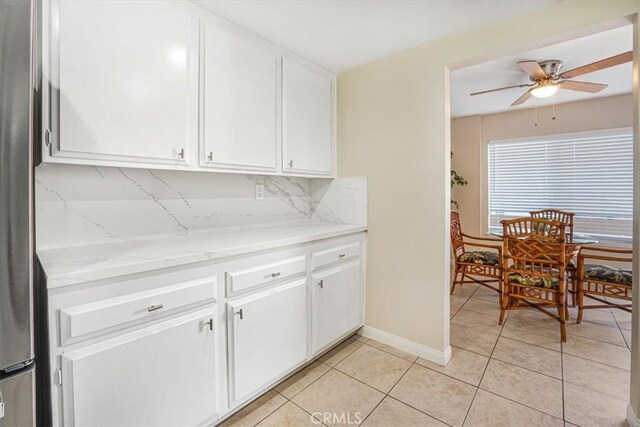 kitchen featuring light tile patterned floors, white cabinets, ceiling fan, and decorative backsplash