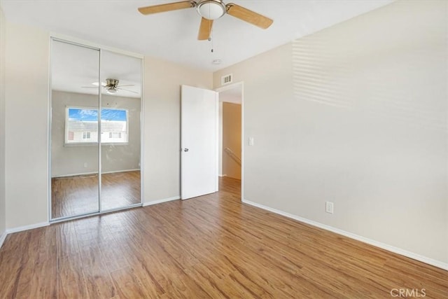 unfurnished bedroom with hardwood / wood-style flooring, ceiling fan, and a closet