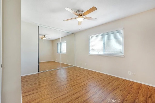 unfurnished bedroom featuring ceiling fan, wood-type flooring, and a closet