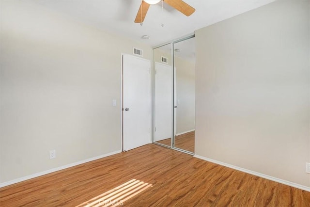 unfurnished bedroom with ceiling fan, wood-type flooring, and a closet