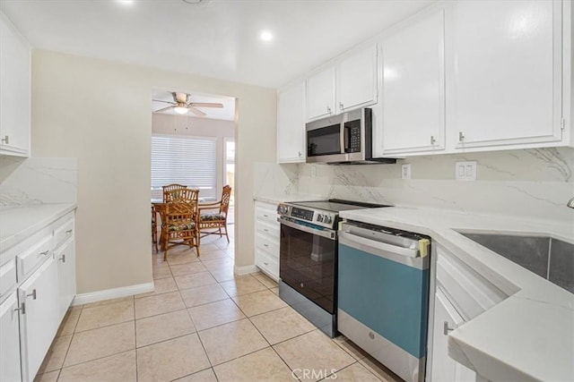 kitchen with light tile patterned flooring, stainless steel appliances, light stone countertops, and white cabinets