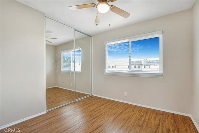 unfurnished bedroom with wood-type flooring, ceiling fan, and a closet