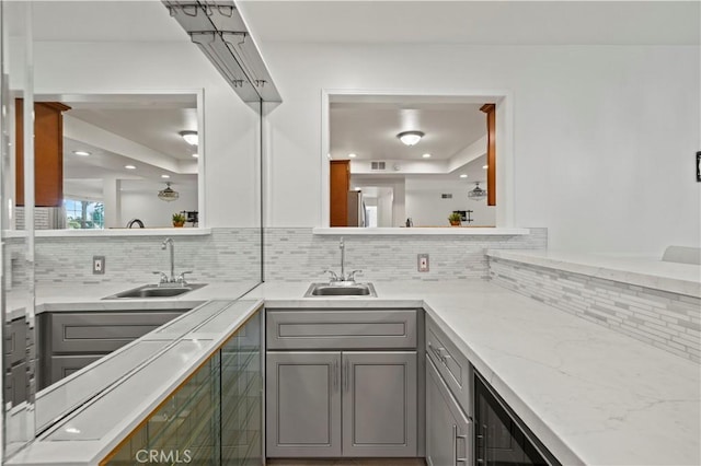 kitchen featuring sink, a tray ceiling, gray cabinets, and tasteful backsplash