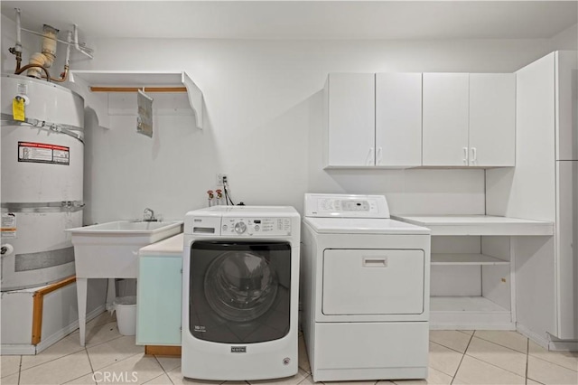 clothes washing area with washing machine and dryer, light tile patterned flooring, cabinets, and water heater