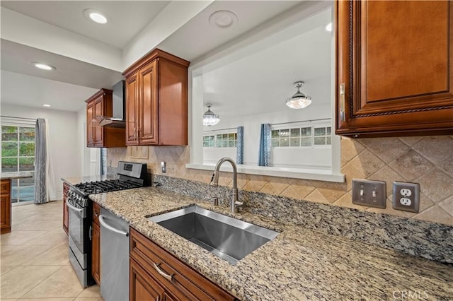 kitchen featuring light stone counters, sink, appliances with stainless steel finishes, and wall chimney exhaust hood