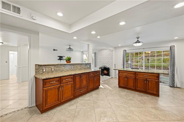 kitchen with light stone countertops, light tile patterned floors, a center island, and a fireplace