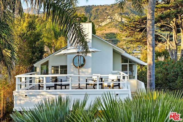 rear view of house featuring a deck with mountain view and a sunroom