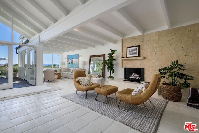 living room with beamed ceiling, a tiled fireplace, and tile patterned flooring